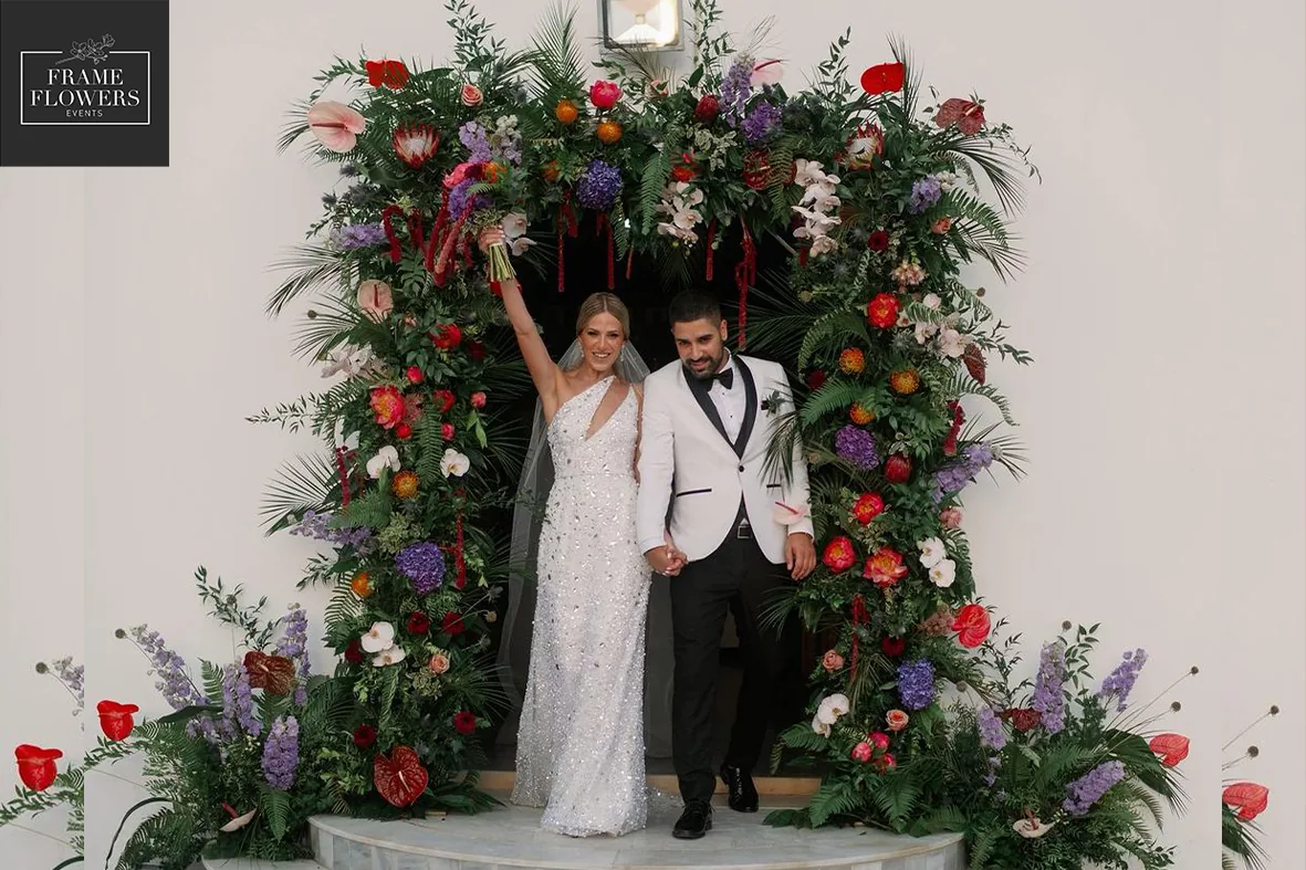 Brautpaar unter einem üppigen Blumenbogen bei einer Hochzeit auf Zypern