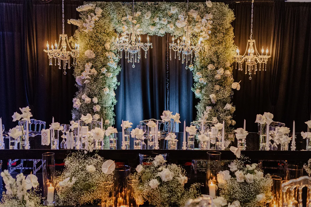 Festsaal mit weißen Blüten, Kronleuchtern und Hochzeitstorte